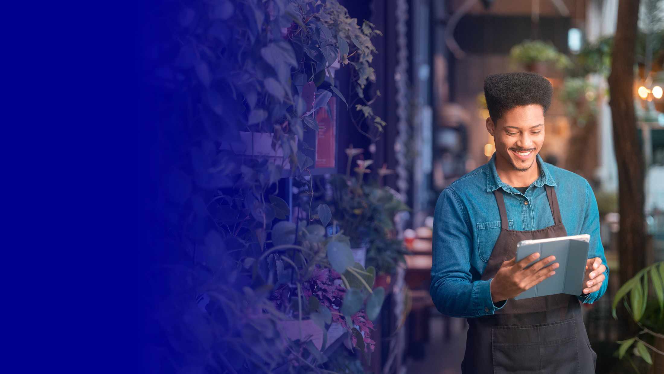 Small business owner holding an iPad in a shop surrounded by plants