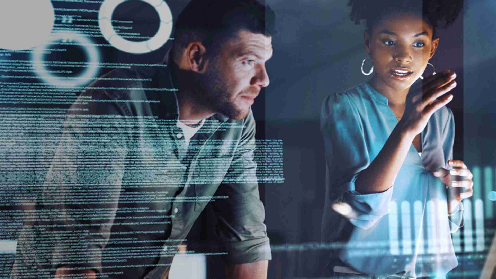Male and female reviewing source codes in front of a screen