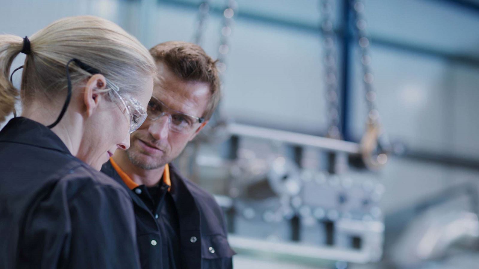 Two people in a factory wearing security glasses
