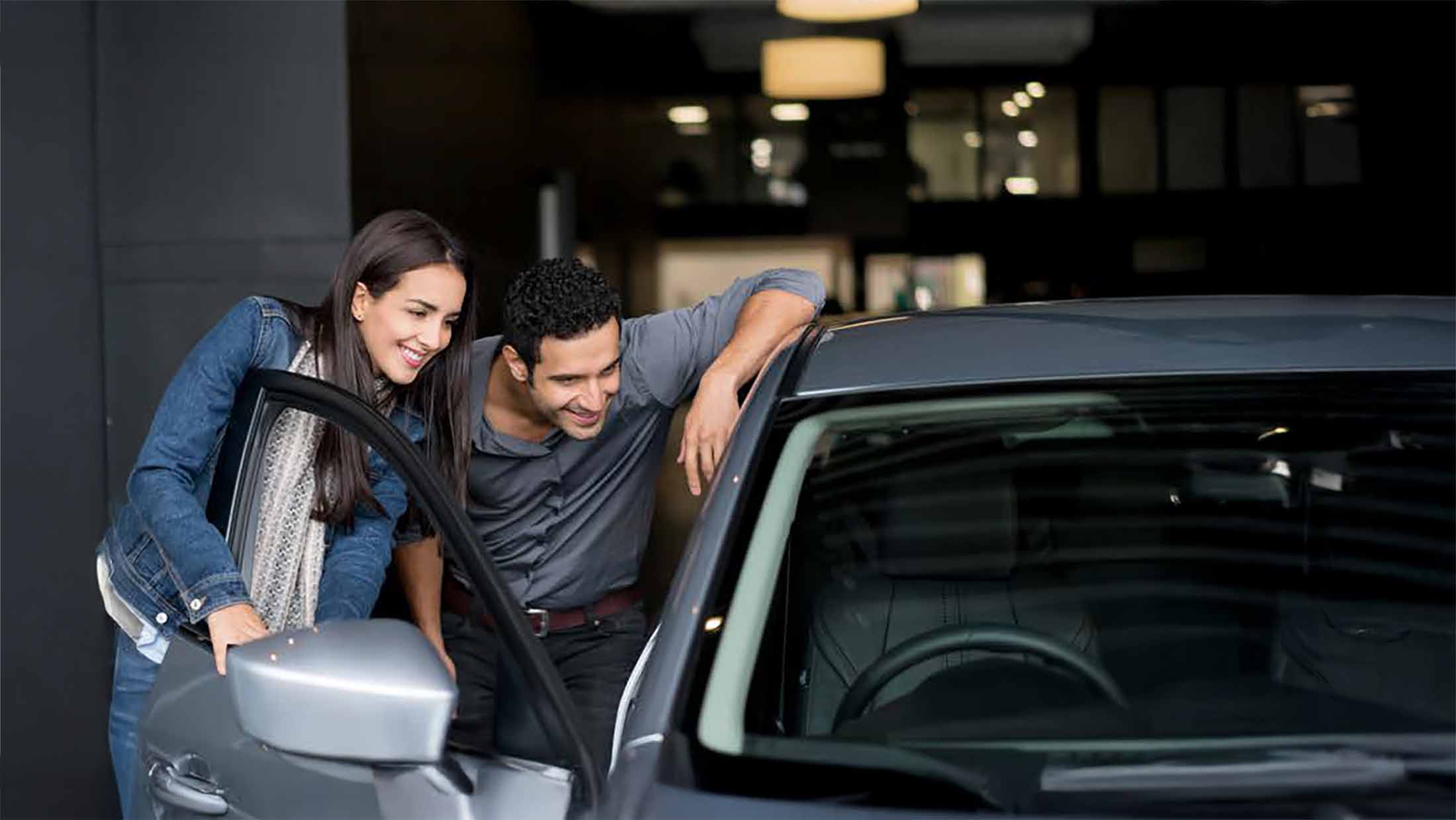 Young couple looking inside the drivers door of a car
