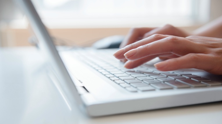 Hands of Hispanic woman typing on laptop