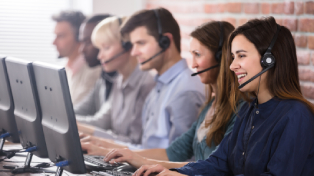 Group of employees at desks on computers with phone headsets on