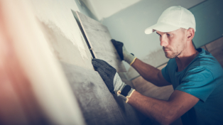 Man wearing a white cap and tiling a wall of a house