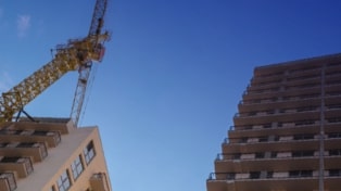 View from the ground looking up at two tower blocks under construction