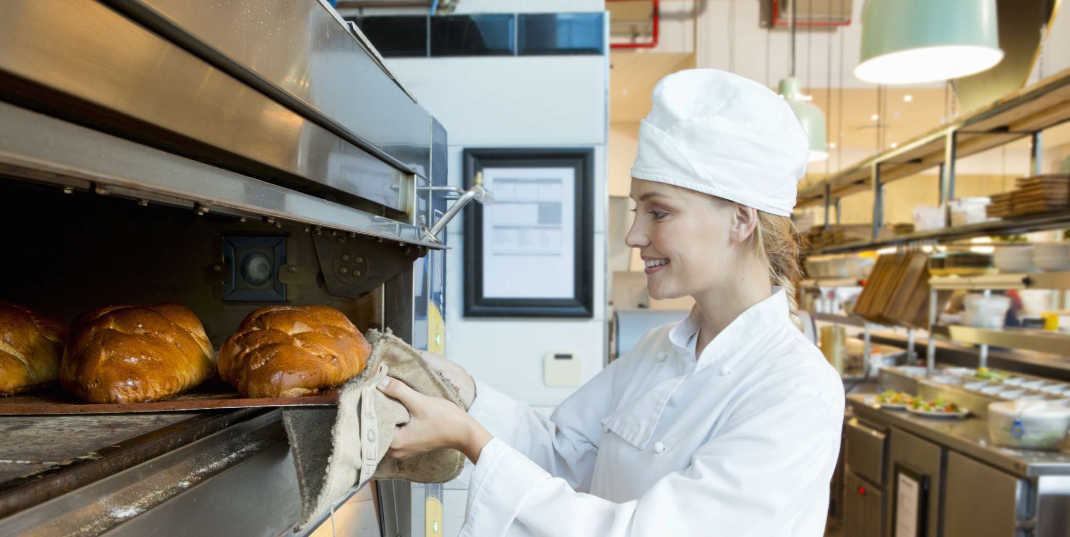 Baker taking bread out of a commercial oven