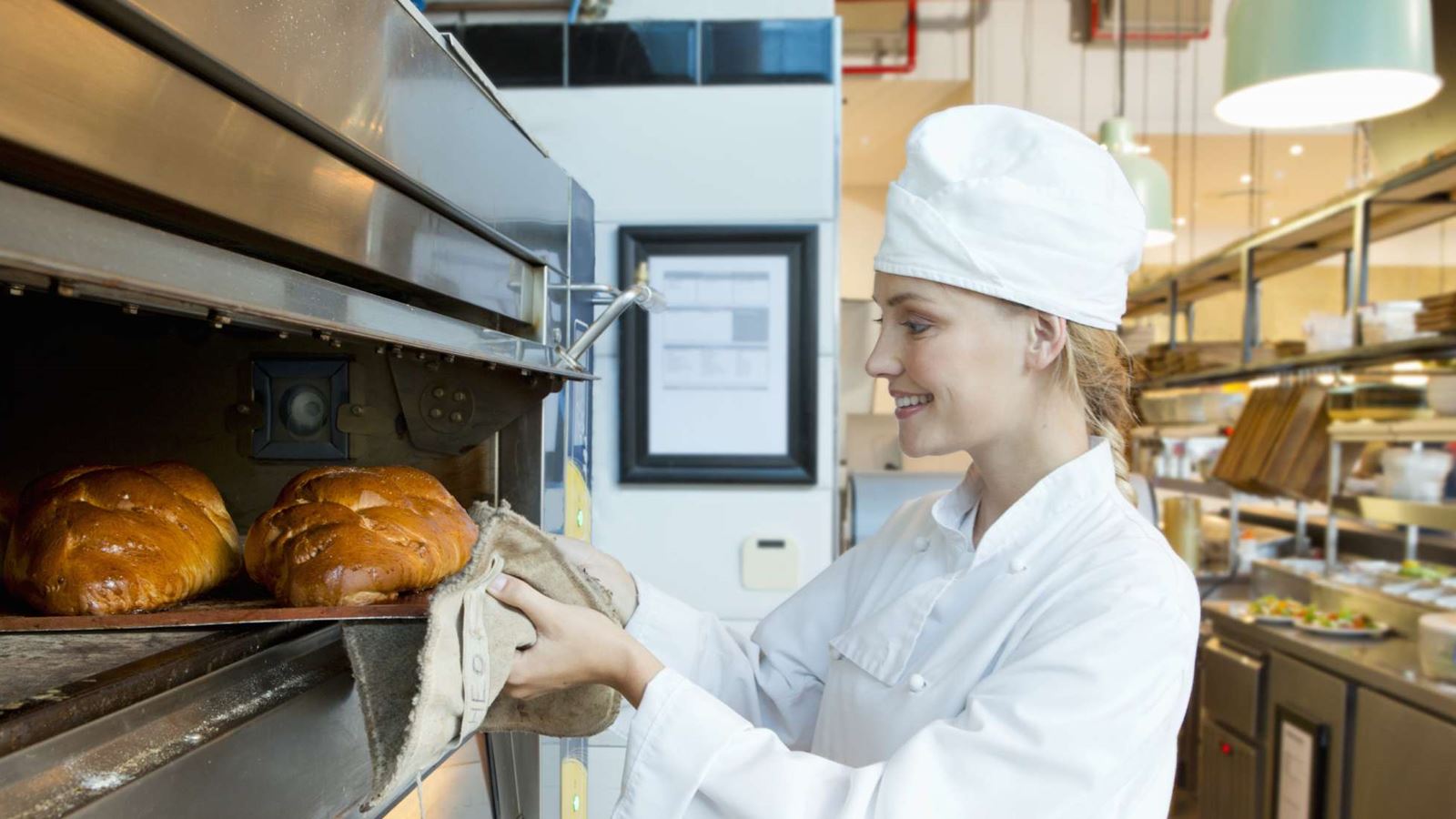 Baker taking bread out of a commercial oven