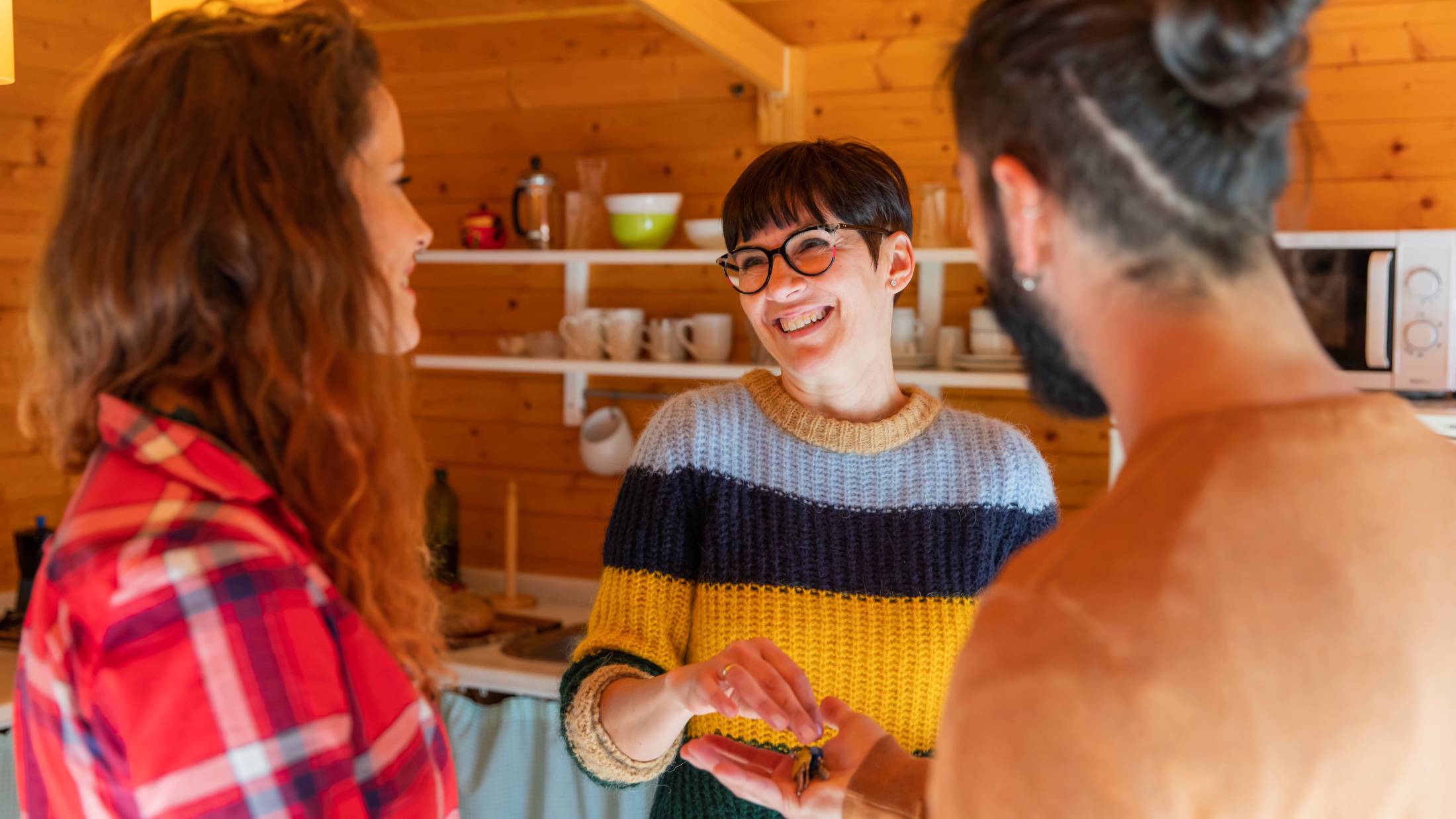 Landlord welcoming young couple in a cabin in the countryside handing over house key
