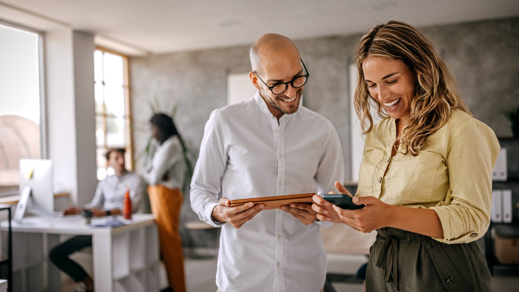 Two colleagues in an office looking at a mobile phone together