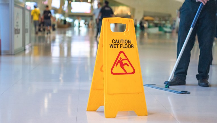 wet floor sign and someone mopping behind