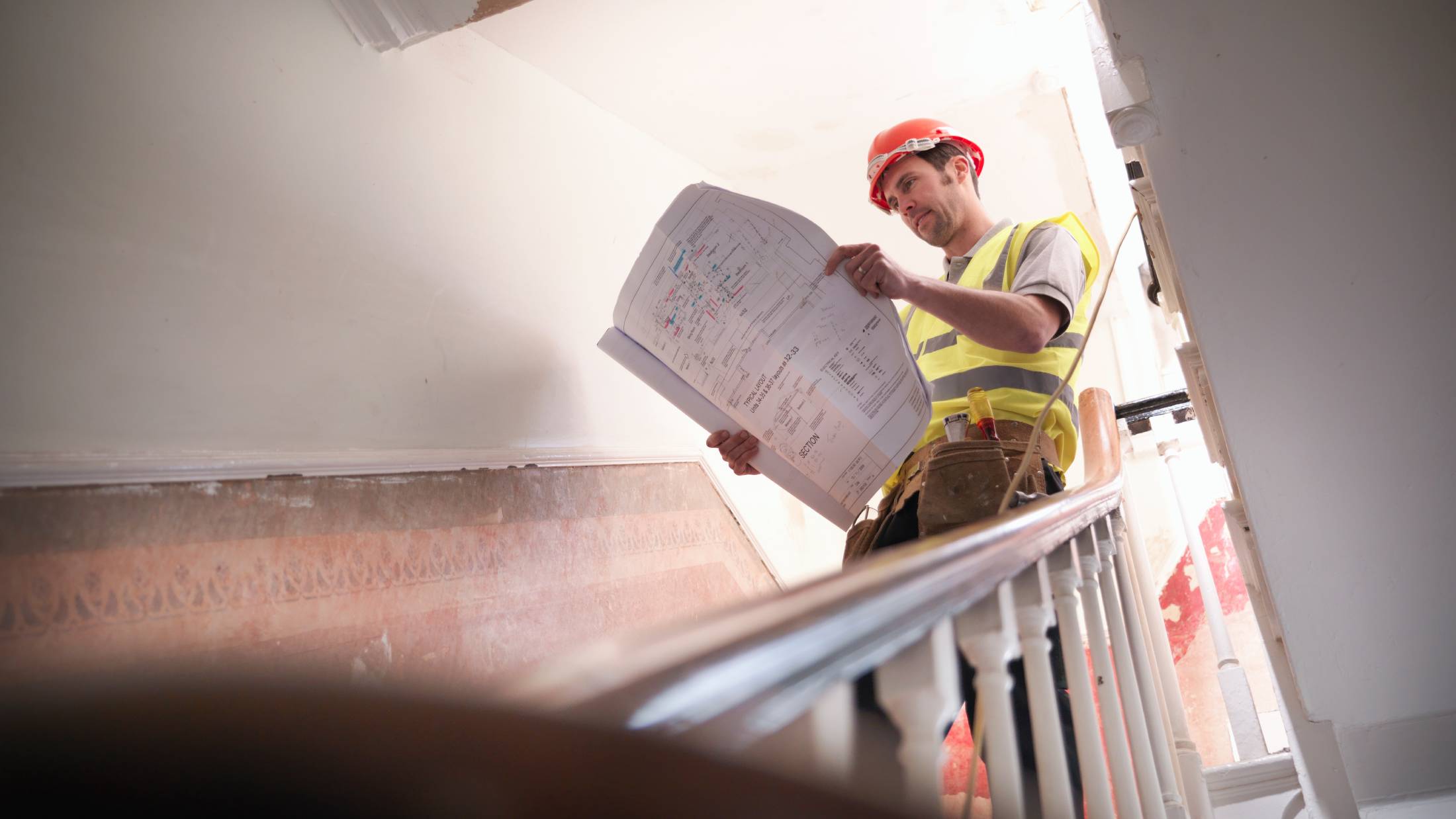 Contractor in hard hat reviewing building plans