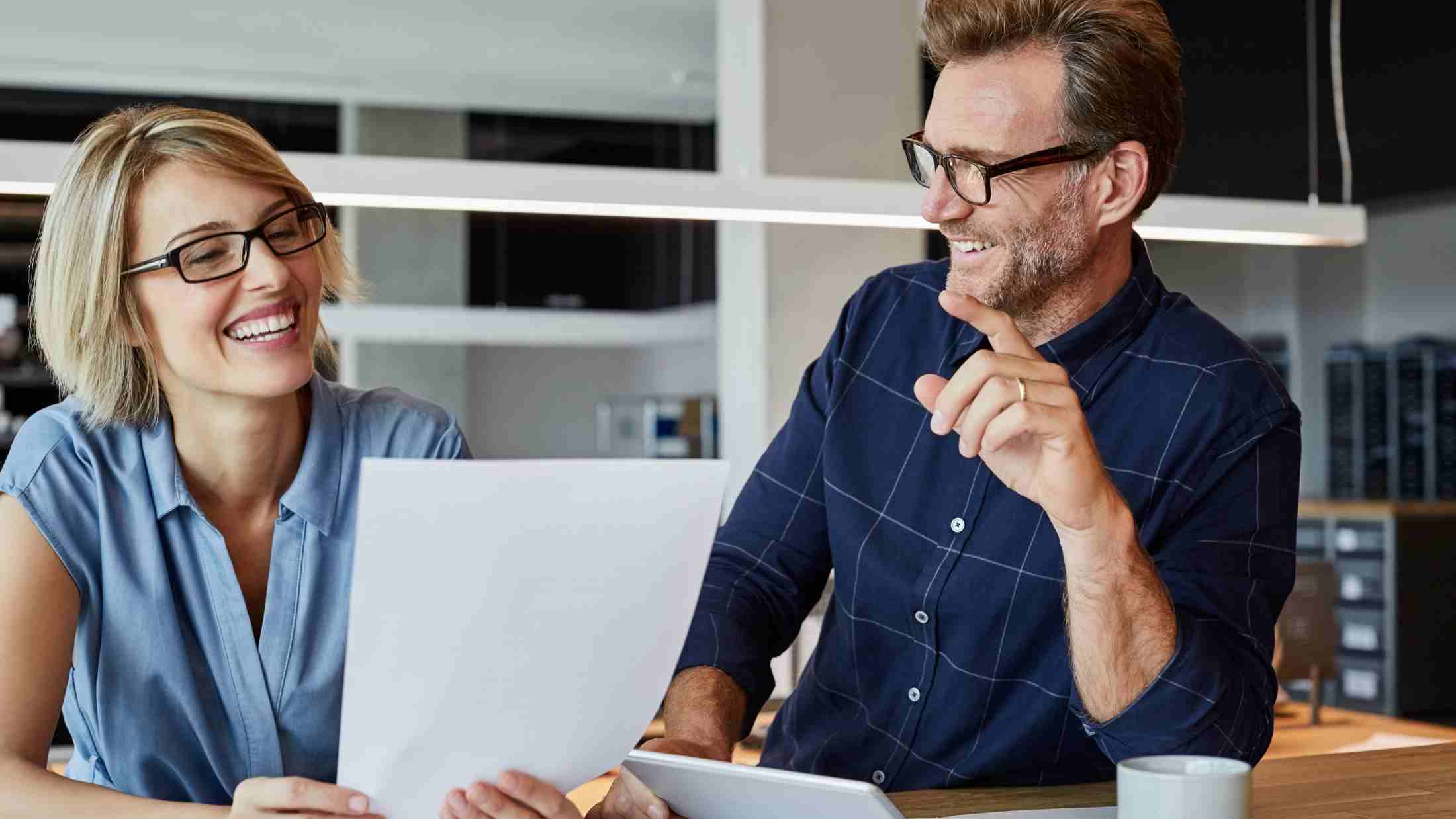 Man and woman in an office looking at a laptop screen
