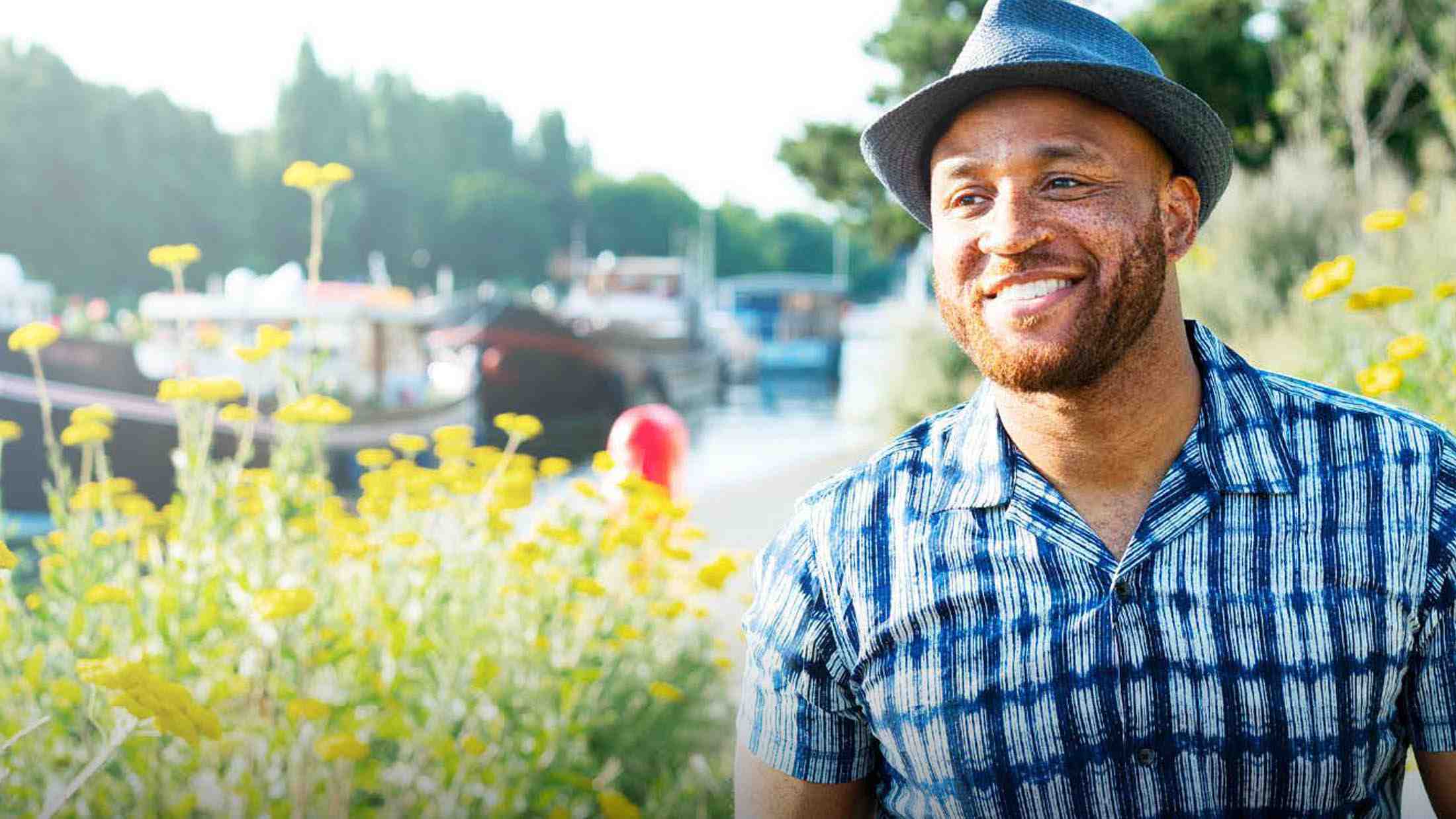 Man in a hat smiling next to a canal
