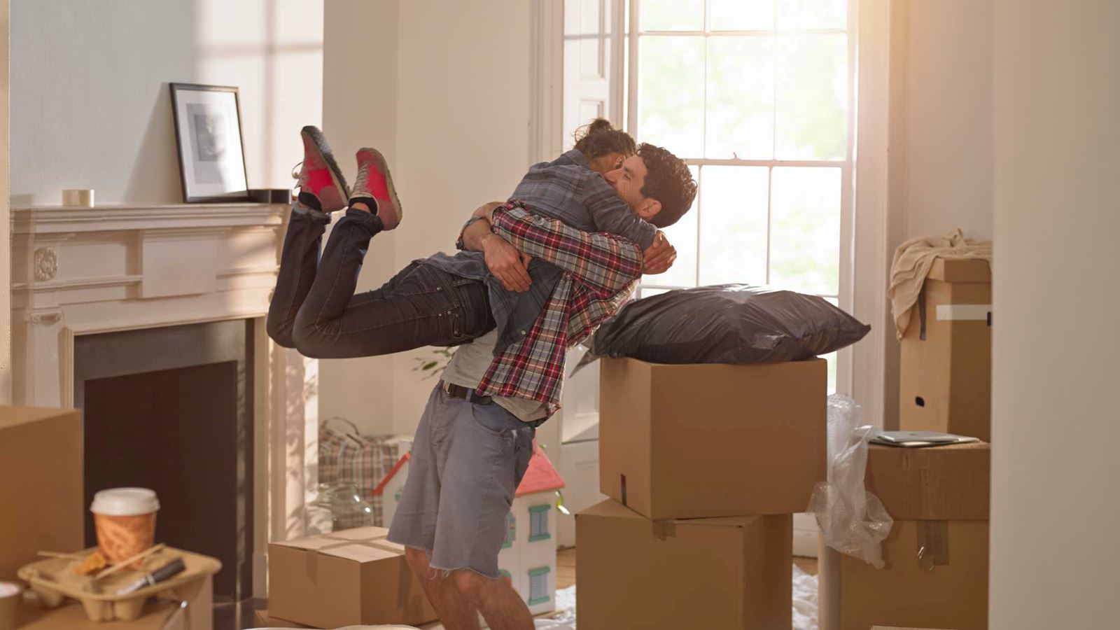 Couple hugging in a house surrounding by moving boxes