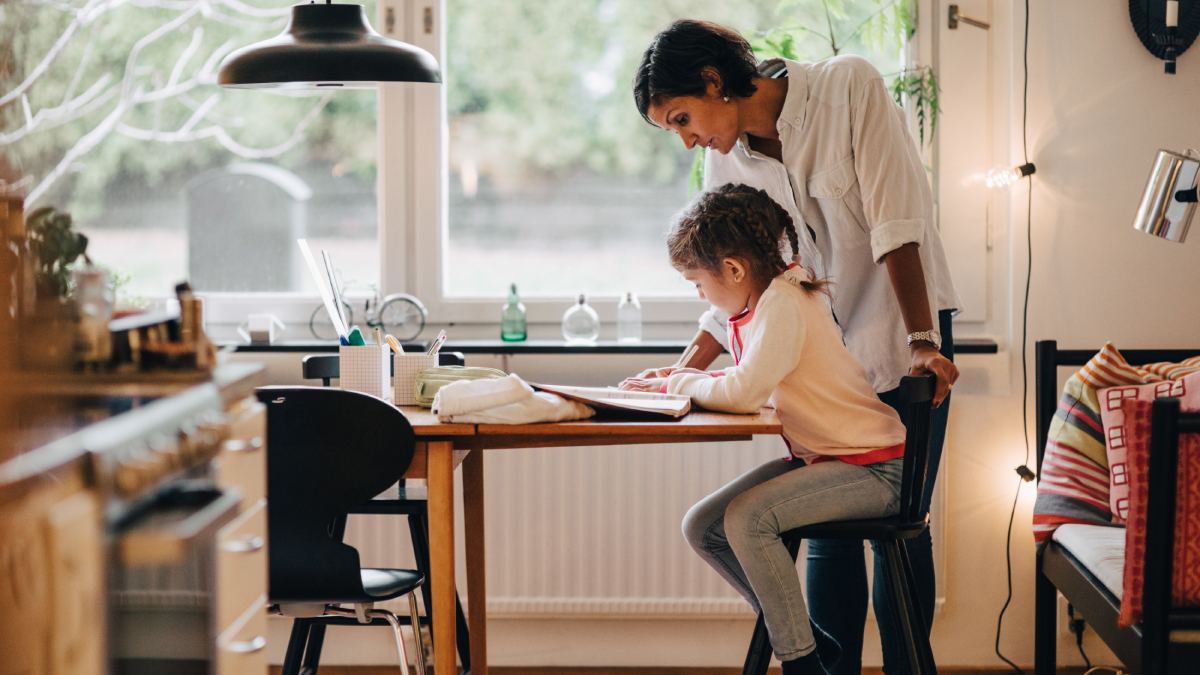 Mother helping her daughter with homework at the kitchen table